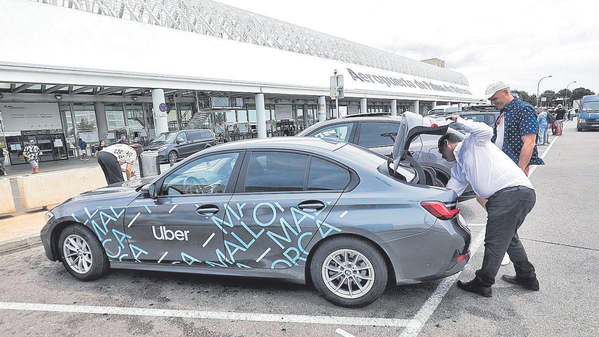 Un conductor de Uber guarda las maletas de un turista en el aeropuerto de Palma.