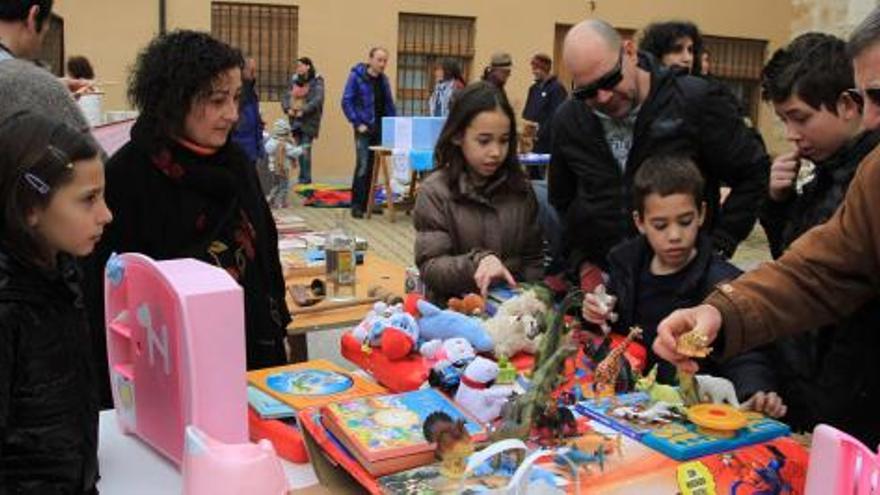 Diversos asistentes fijan su atención en los juguetes, uno de los productos aportados en el singular mercadillo celebrado en Olivares.