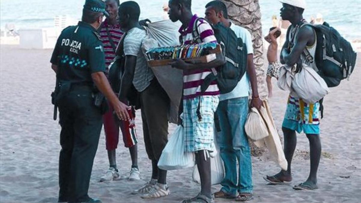 Un policía local intercepta a un grupo de manteros en la playa de Calafell (Baix Penedès), el verano pasado.