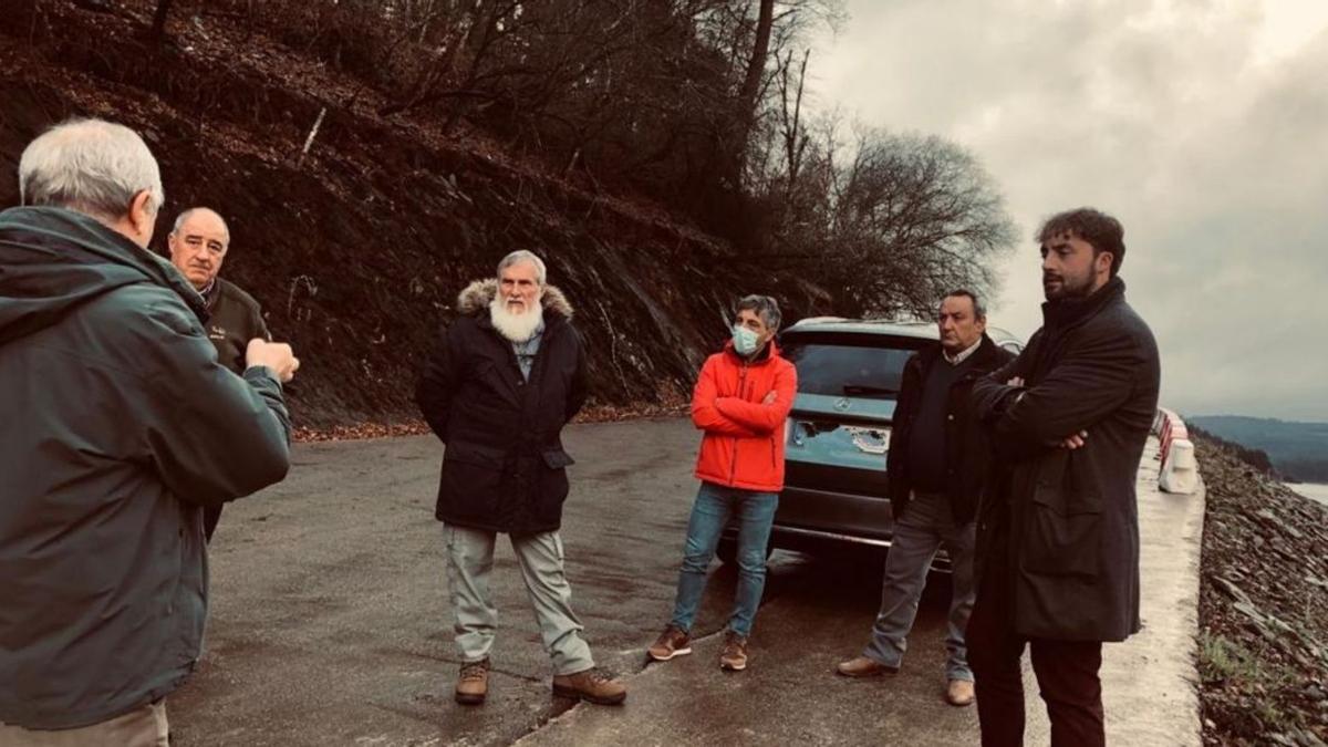 Xosé Luis Rivas, Álex Fiuza y Manuel Adán. con vecinos de Loño y Beigondo, en la pista de acceso al embarcadero.