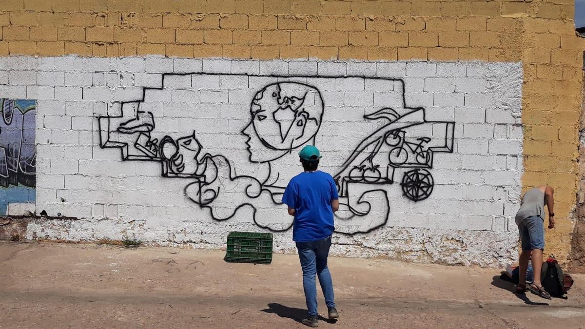 Estudiante de Bellas Artes pintando uno de los muros del abergue,, en una imagen de archivo