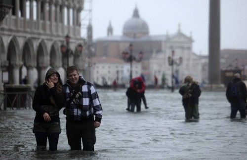 La gente camina a través de una calle inundada durante el período de las inundaciones en Venecia