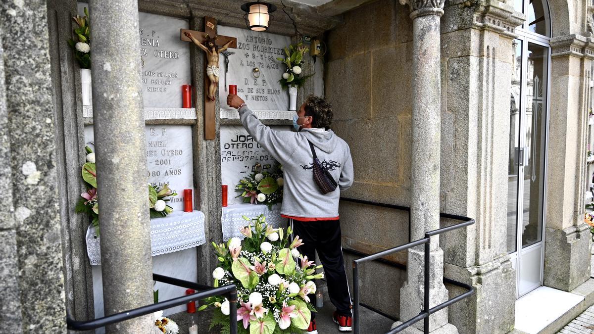 Un joven coloca una vela ante un nicho en el cementerio de Marcón/ Rafa Vázquez