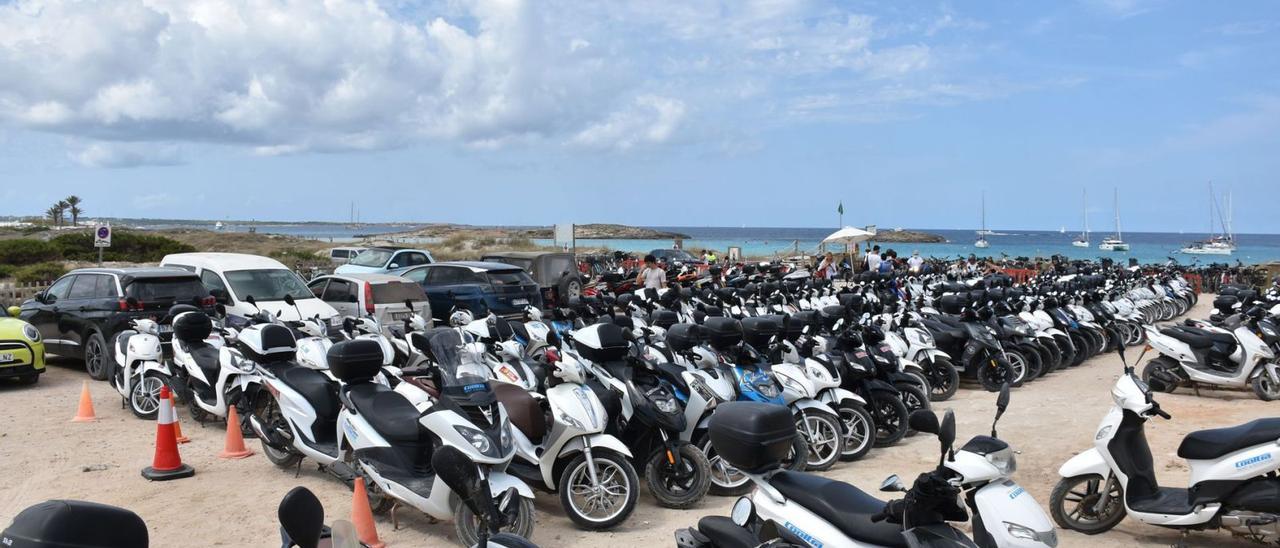 Motos y coches, muchos de alquiler, estacionados en uno de los aparcamientos de ses Illetes. | CÉSAR NAVARRO