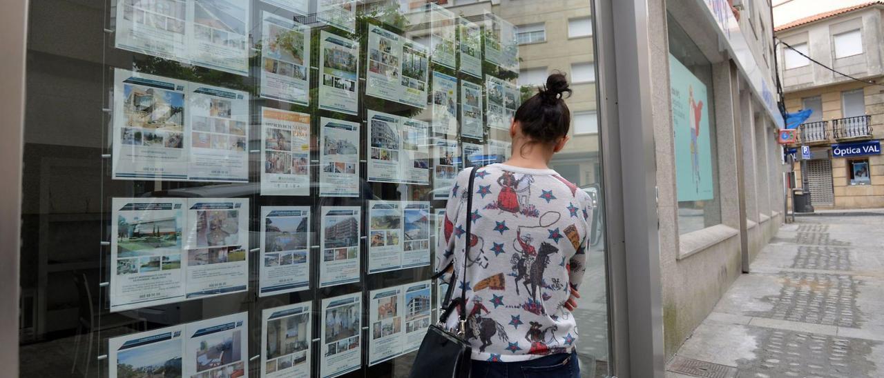 Una mujer mira el escaparate, lleno de ofertas, de una inmobiliaria. | | GUSTAVO SANTOS