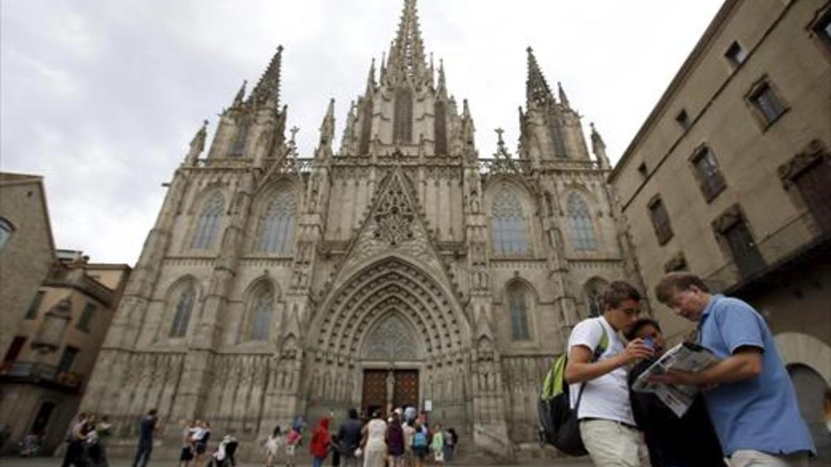 Unos turistas consultan un plano de la ciudad delante de la Catedral.