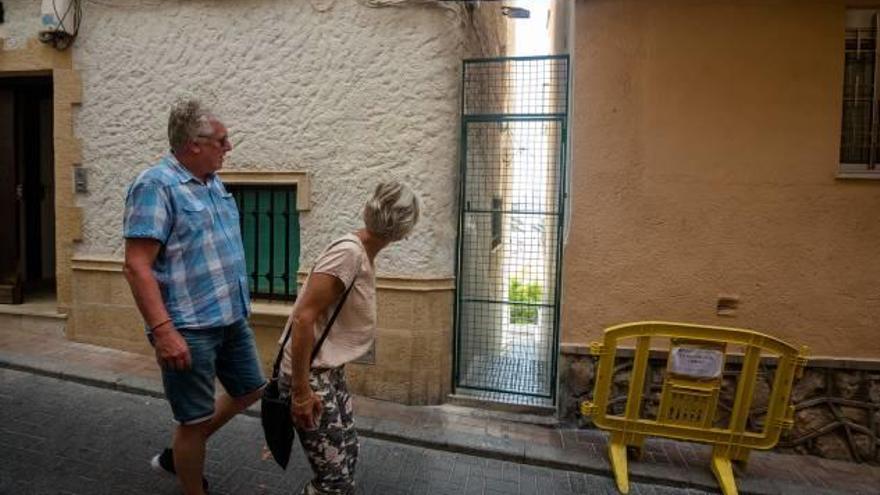 Dos personas observan la puerta con reja colocada en el callejón.