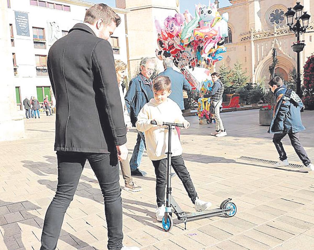 Un niño, con su patinete en la plaza Mayor de Castelló.