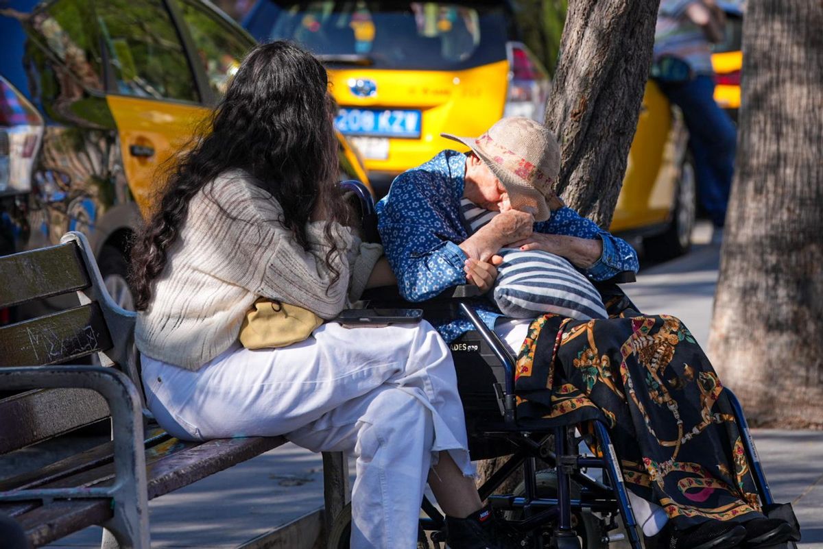 Unas mujeres se refugian de las altas temperaturas en un banco a la sombra en Barcelona.
