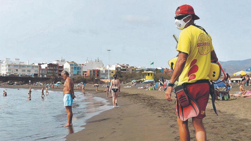 Grupos de personas disfrutan de un día de playa en Melenara, Gran Canaria.