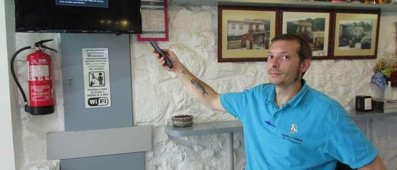 Víctor Pascual, intentando encender la televisión en el restaurante El Chisperu, ayer.