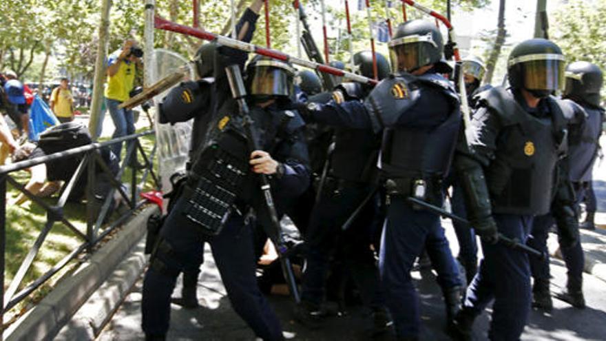 Agentes detienen una valla lanzada por manifestantes