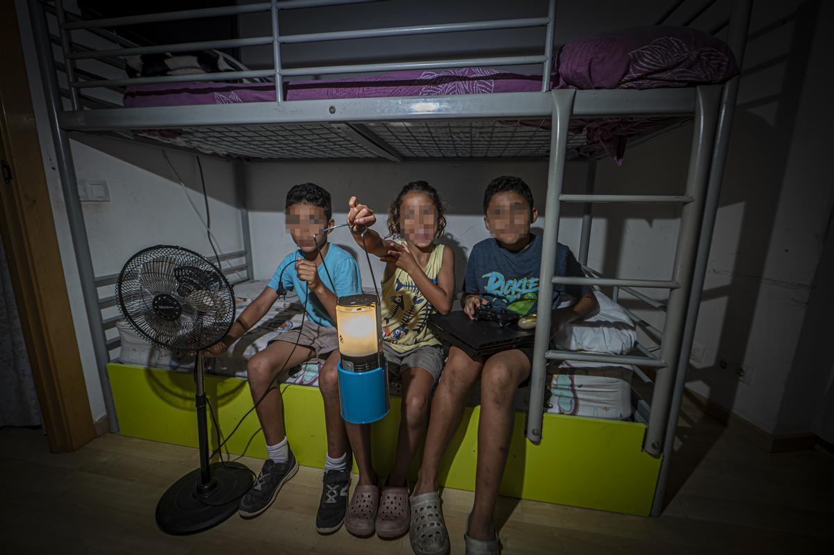 Los tres hijos de Fouzia y Hicham mostrando con una luz de gas dos objetos inutilizables: el ventilador y la PlayStation