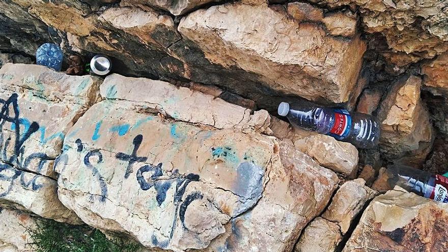 Residuos y pintadas en la cala del Tangó y la bolsa repleta de basura retirada de este litoral.