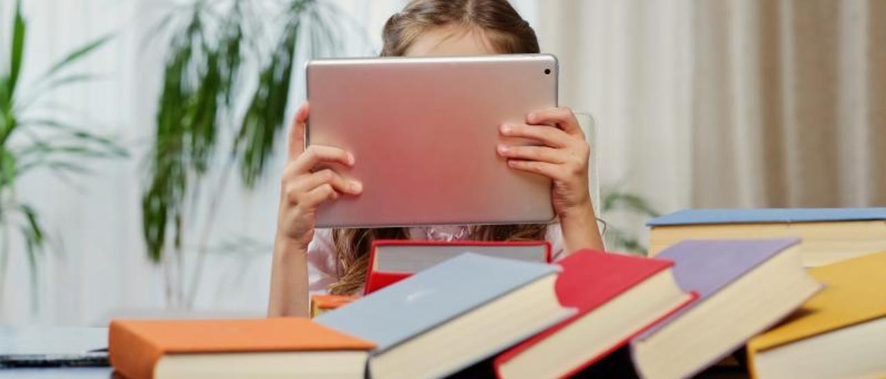 Una niña lee en su tabletdesdeñando los libros.