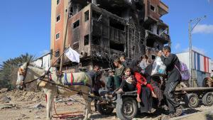 Una familia escapa del horror frente a un edificio bombardeado en la Fraja de Gaza.