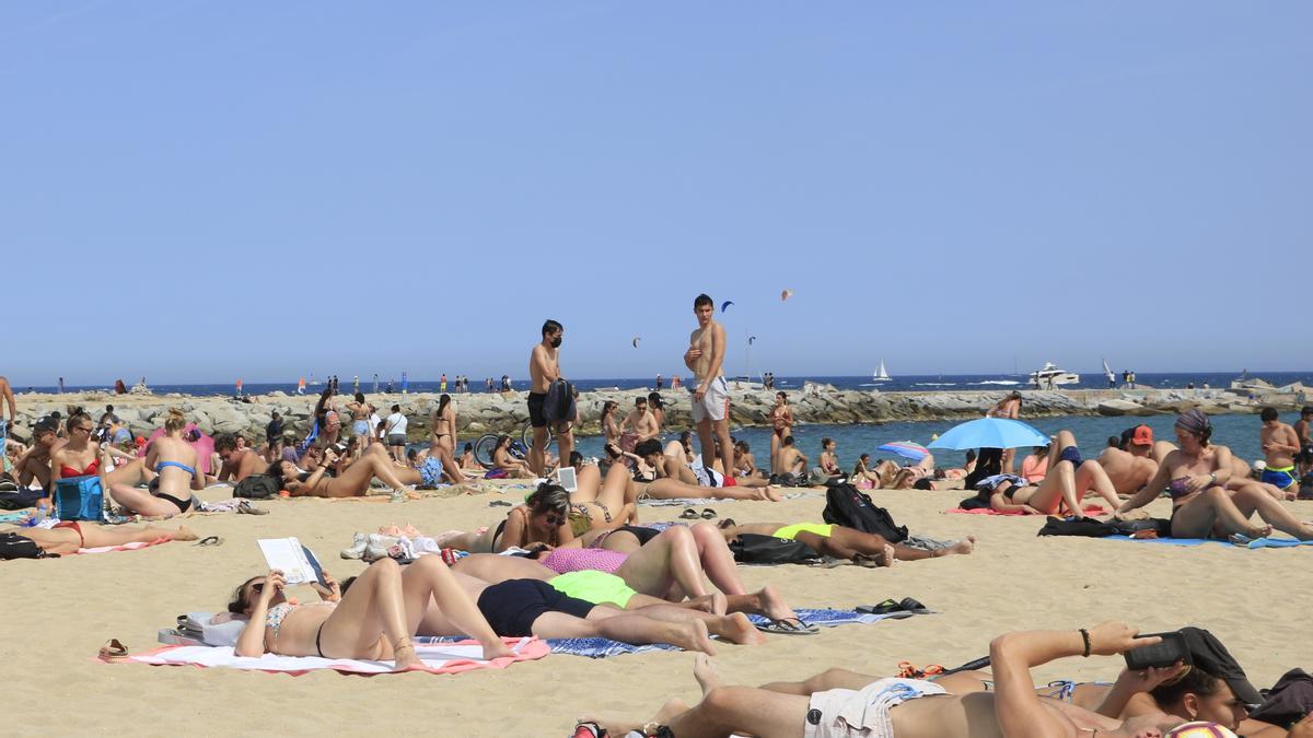 Persones prenent el sol a la platja del Bogatell de Barcelona en un dissabte de maig