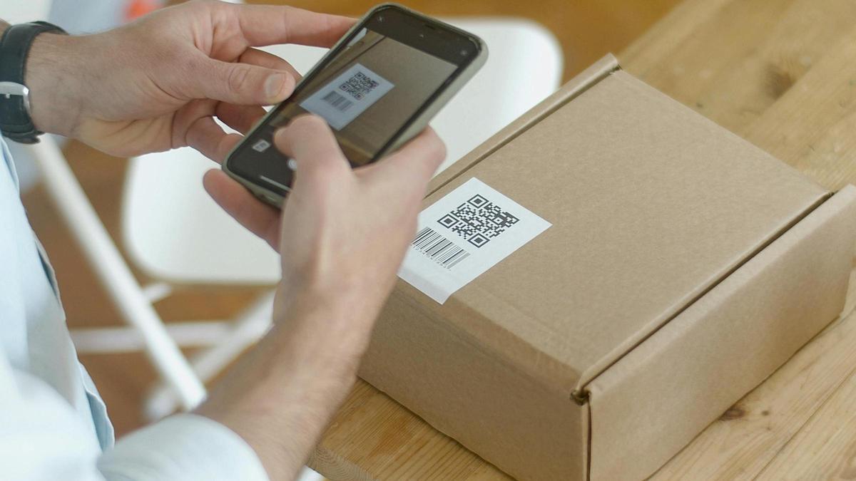 Una persona escanea el código de barras de un paquete con un teléfono móvil.