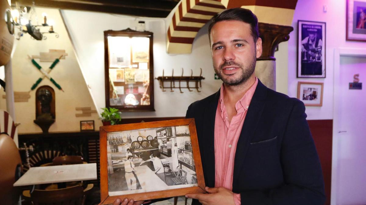 Jesús Murillo, propietario de la taberna Bar Santa Marina, muestra una foto de su abuelo trabajando en el establecimiento.