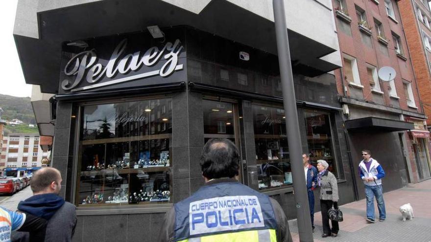 Un agente de policía, ante la joyería atracada en Mieres en abril de 2012.