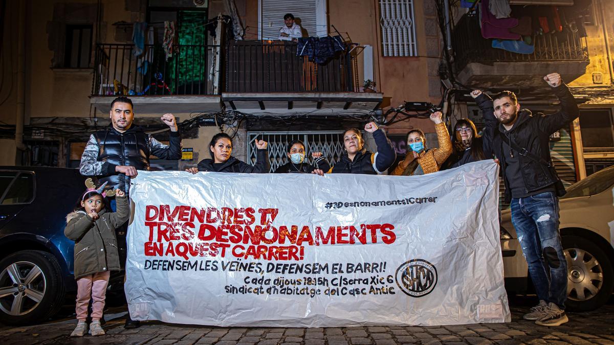 Vecinos del Casc Antic sostienen la pancarta que denuncia los tres desahucios previstos en la calle del Portal Nou para este viernes.