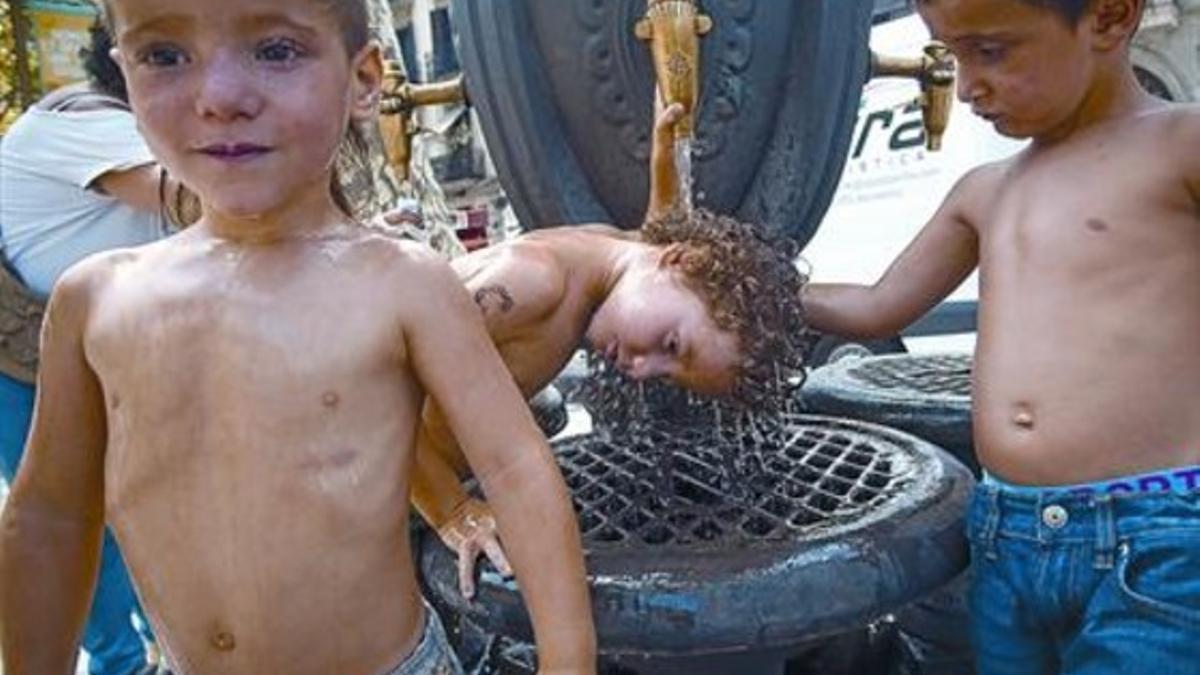 Tres niños en la fuente de Canaletes, en la Rambla de Barcelona, ayer.