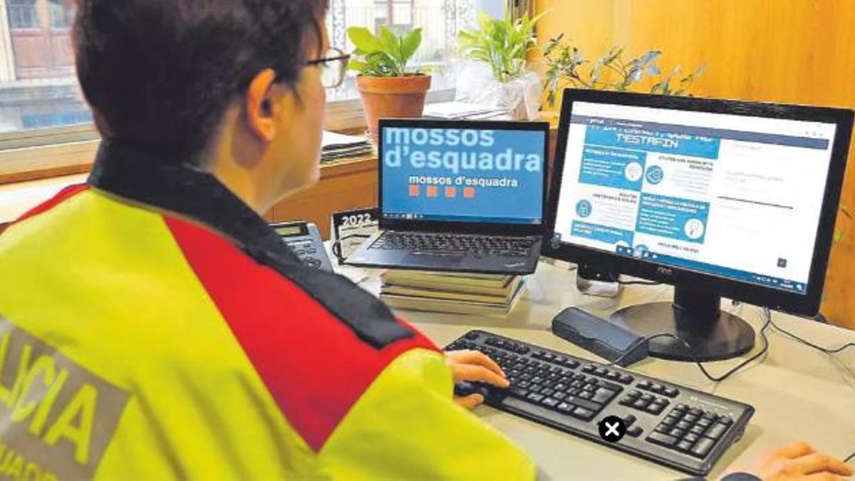 Una agent dels Mossos d'Esquadra consulta un web per evitar estafes informàtiques.