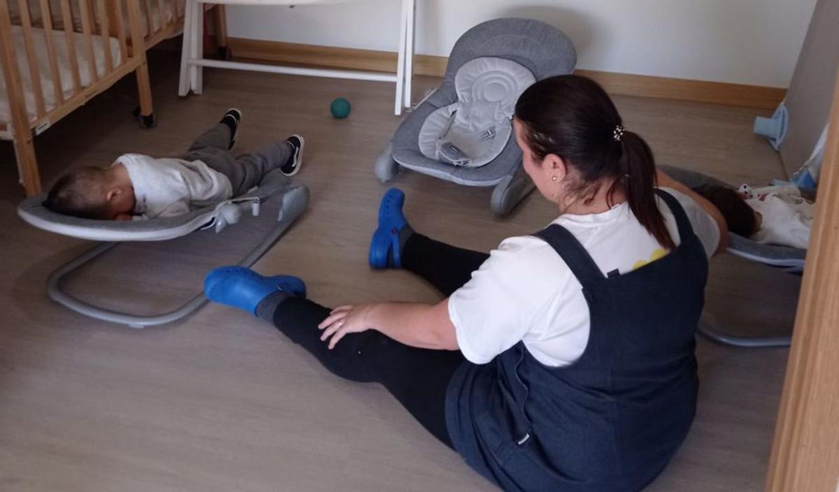 Una cuidadora en servicios mínimos, junto a un bebé en el centro de Sariego.