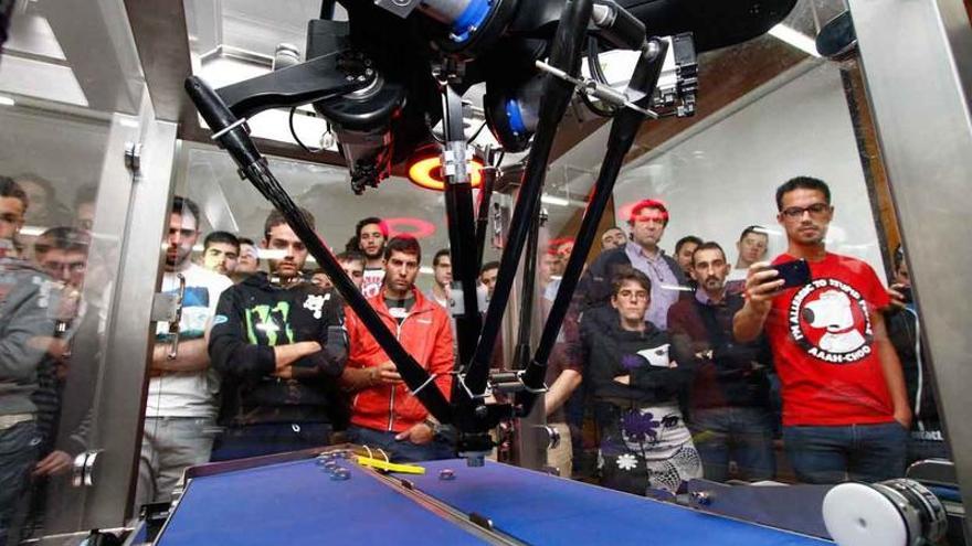 Alumnos de la Escuela Politécnica de la capital observan el trabajo de un robot de visión artificial. Abajo, sistemas de seguridad de la maquinaria.