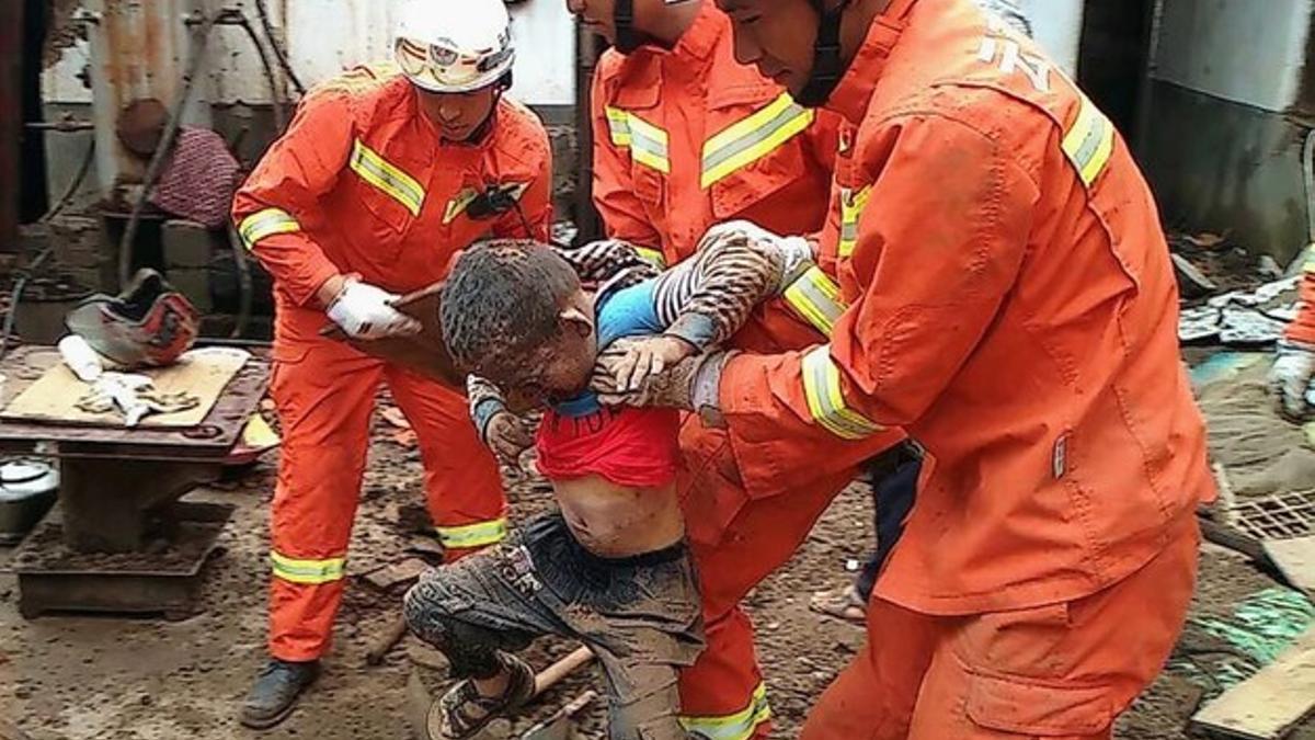 Los equipos de rescate sostienen a un joven que estaba bajo los escombros, en la localidad de Longtoushan.