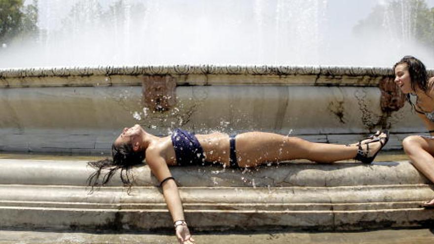 Dos turistas se refrescan en una fuente.