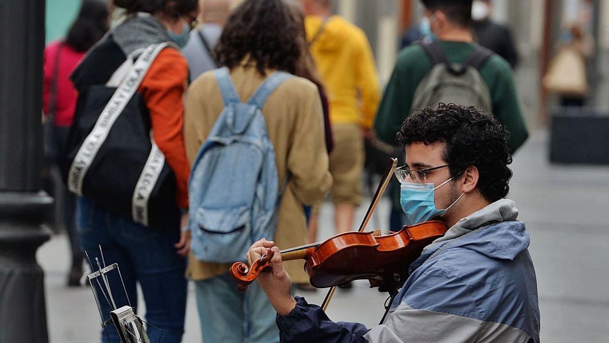 Un joven con mascarilla toca el violín en Triana. | | JOSÉ CARLOS GUERRA