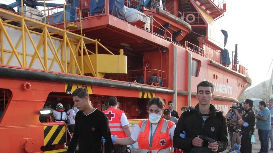 Una voluntaria de Cruz Roja acompaña a dos jóvenes inmigrantes rescatados en Cartagena.