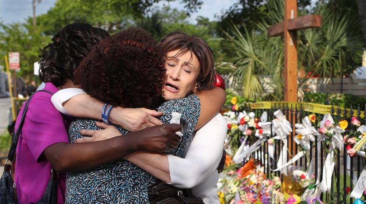 Tres mujeres se abrazan junto a la ofrenda floral frente a la iglesia metodista, en Charleston, este sábado. Tres mujeres se abrazan junto a la ofrenda floral frente a la iglesia metodista, en Charleston, este sábado.