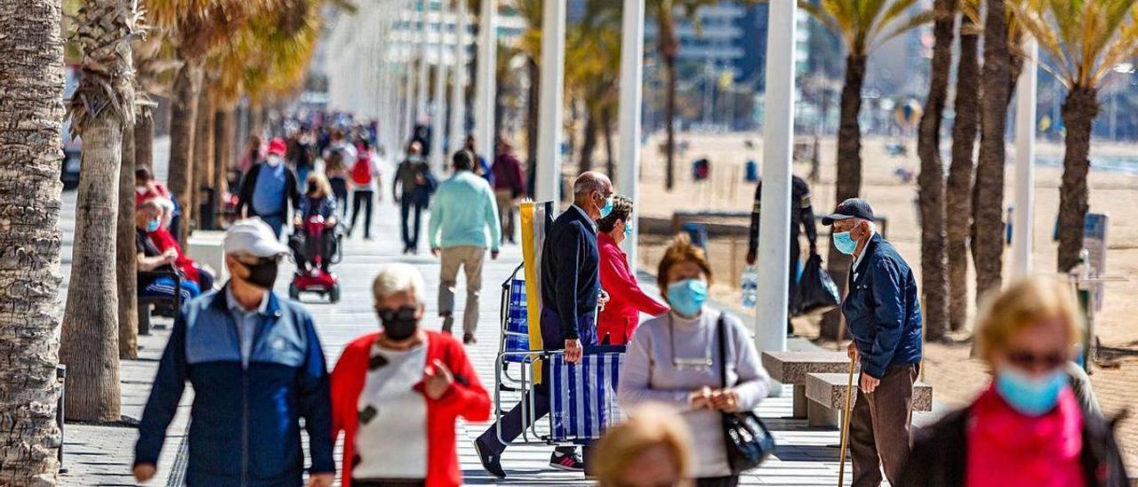 Turistas y vecinos pasean por primera línea de playa de Benidorm, en una imagen de archivo.