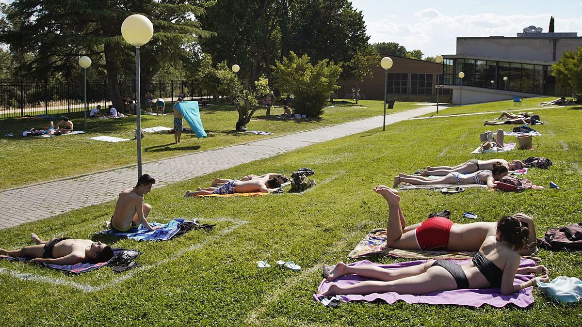 Los bañistas ocupan las parcelas habilitadas en el césped de la piscina Sindical. | Jose Luis Fernández