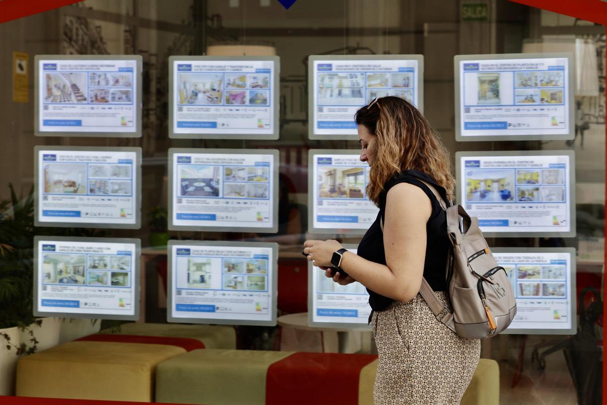 Una mujer pasa por delante de las ofertas de venta y alquiler de viviendas de una inmobiliaria de la ciudad de Castelló.