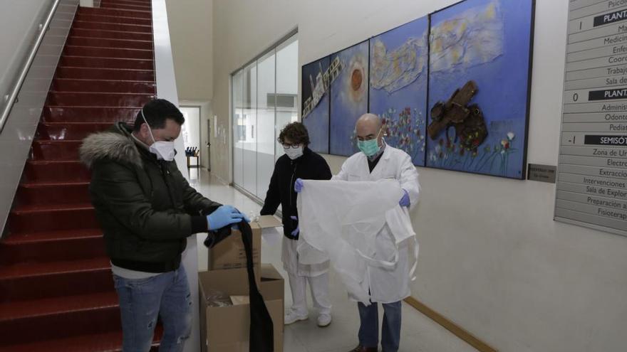 Sergio García entrega mascarillas y batas al coordinador del centro de salud de La Ería, Félix Muñoz, y a la enfermera, María José Roces.