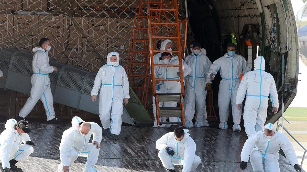 Trabajadores con trajes de protección descargan equipos sanitarios procedentes de China, en el aeropuerto de Paris-Vatry.