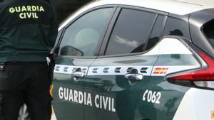 Un agente de la Guardia Civil, junto a un vehículo del cuerpo.