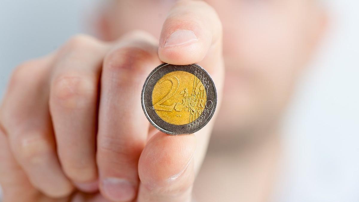 Una persona muestra una moneda de dos euros.