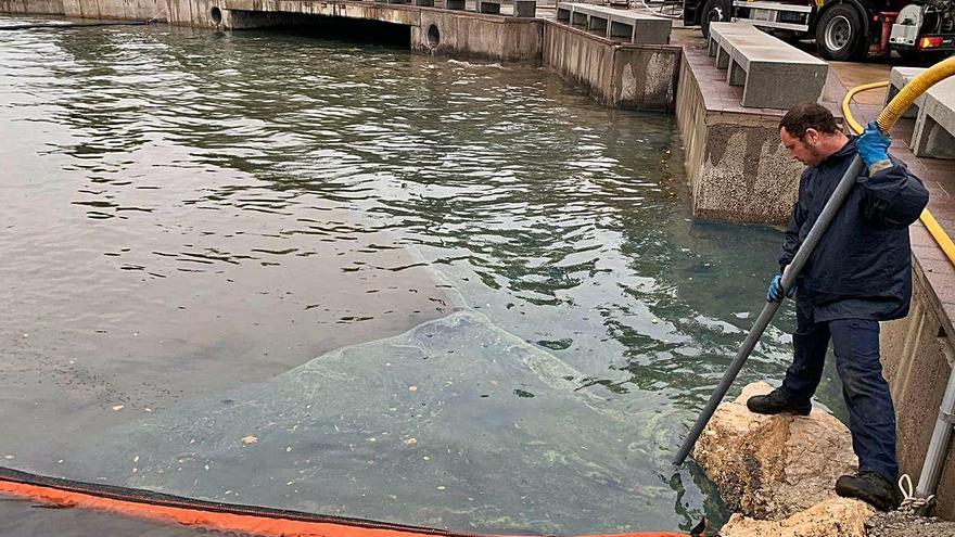 Un operari succiona el gasoil que va arribar al mar a través de la riera el Ginjoler.