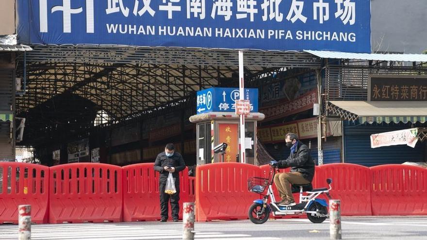 Dos ciudadanos pasan por la entrada del mercado de mariscos Huanan en Wuhan.