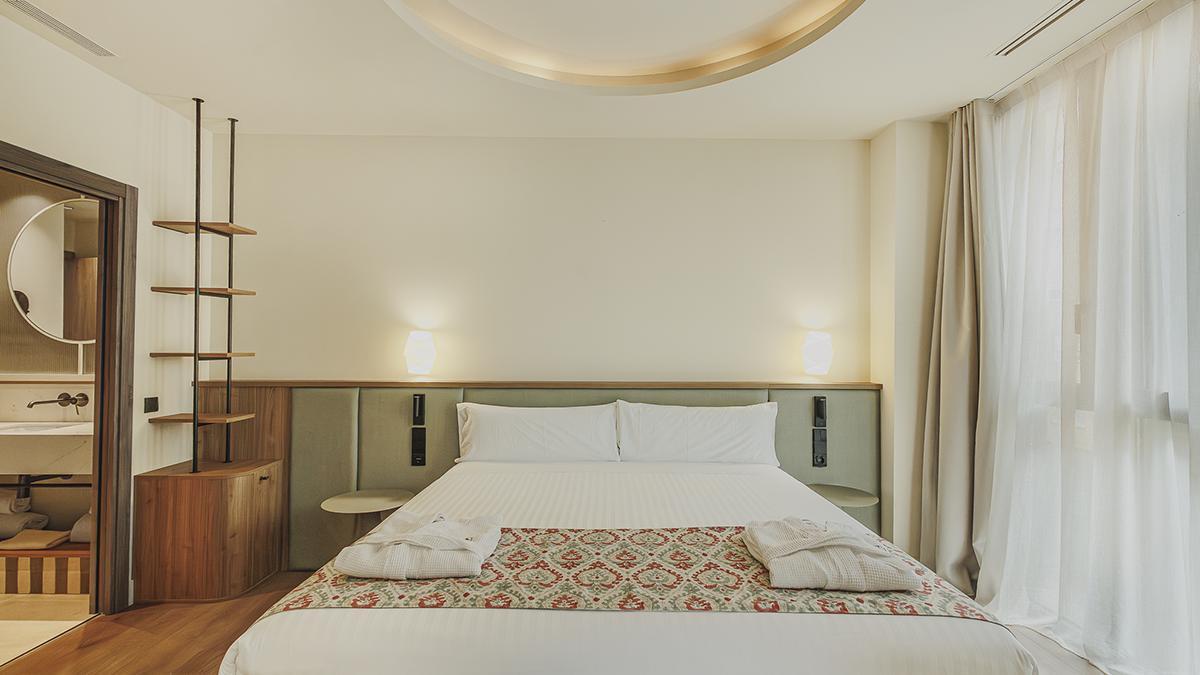 Una de las 170 habitaciones del hotel, con un interiorismo en tonos suaves, madera y detalles textiles de inspiración mediterránea.