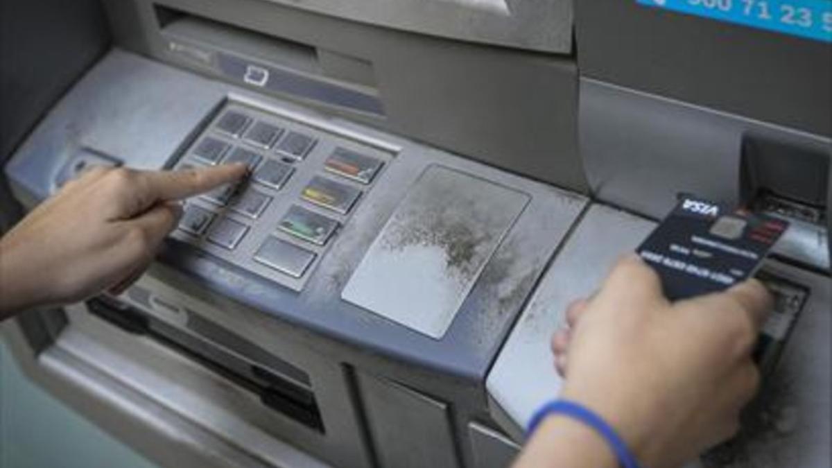 Servicio 8Una clienta retira dinero en efectivo de un cajero, en Barcelona.