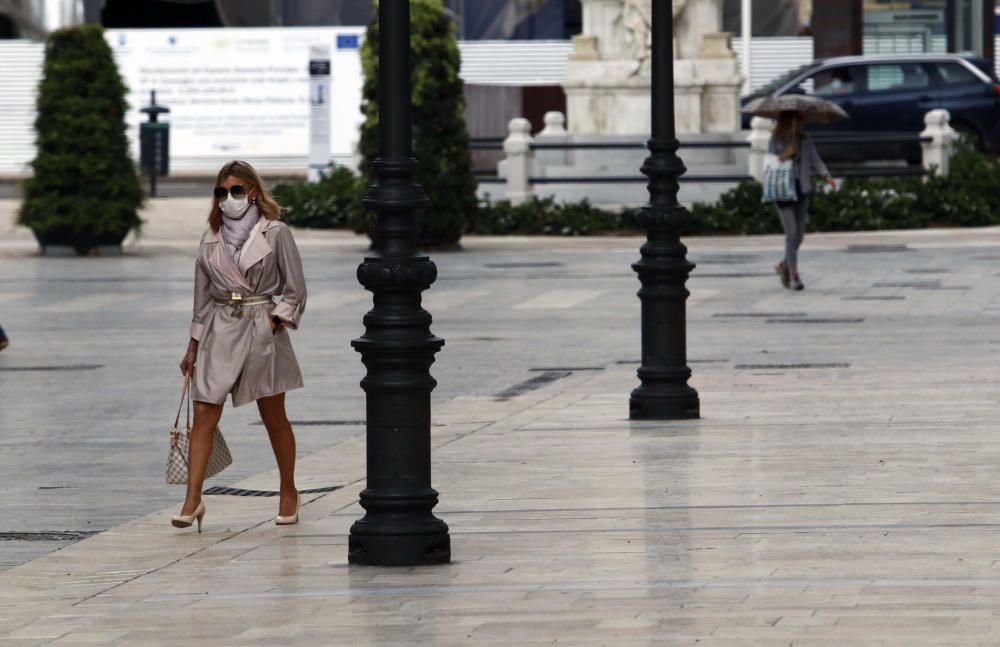 Imágenes de una lluviosa mañana de jueves en el centro de Málaga, donde al paisaje ya habitual de pocas personas y la mayoría de ellas con guantes y mascarillas se le han añadido los preparativos de bares, cafeterías y terrazas que se preparan para el inminente cambio de fase de la desescalada de la ciudad.