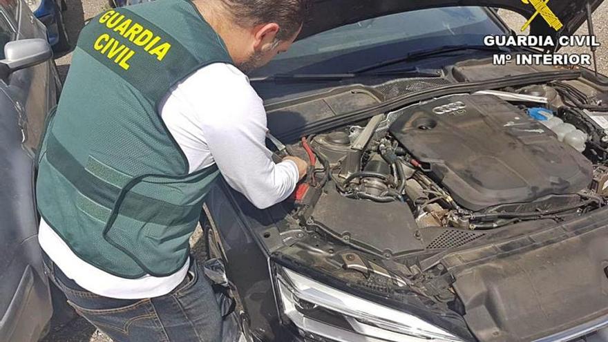 Un guardia civil examina uno de los vehículos recuperados.