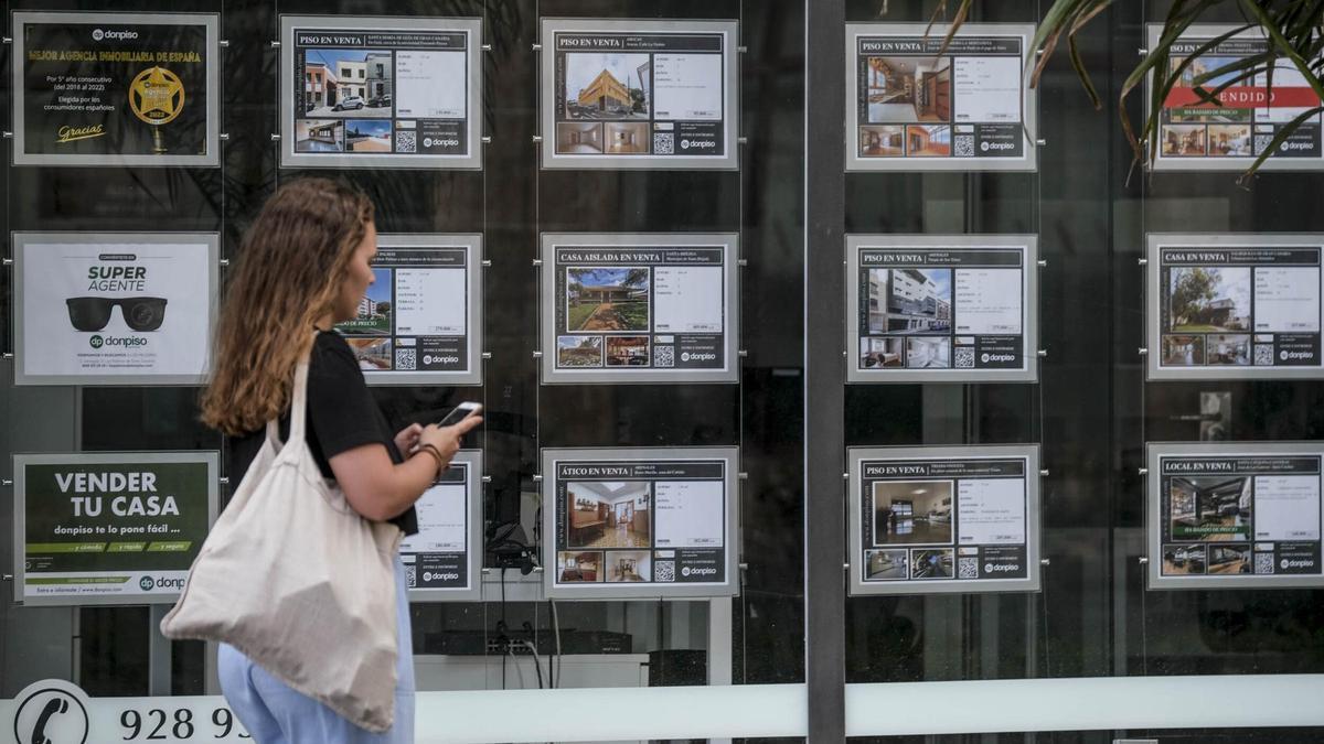 Una mujer pasa frente a una inmobiliaria.