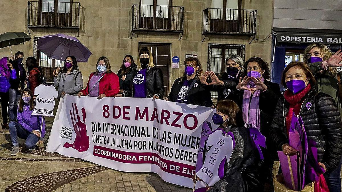 La Plataforma Feminista en la plaza de la Montañeta en Alicante y la Corporación de Benidorm bajo la pancarta conmemorativa. | ALEX DOMÍNGUEZ