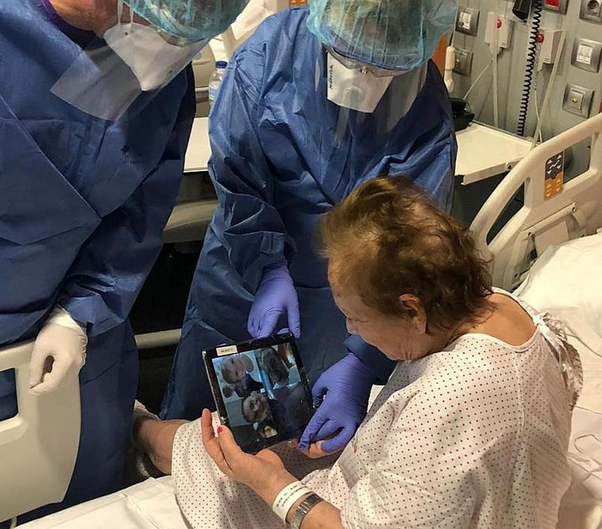 Dos enfermeras ayudan a una paciente del Hospital Sant Joan de Déu, de Palma, a hablar, por videollamada, con su familia.